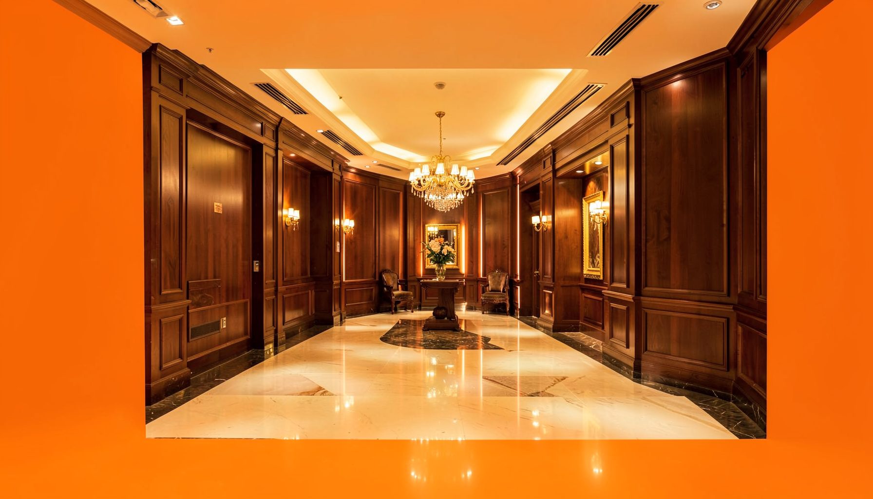 A polished hotel lobby with warm amber lighting and rich wood paneling, conveying an upscale hospitality atmosphere