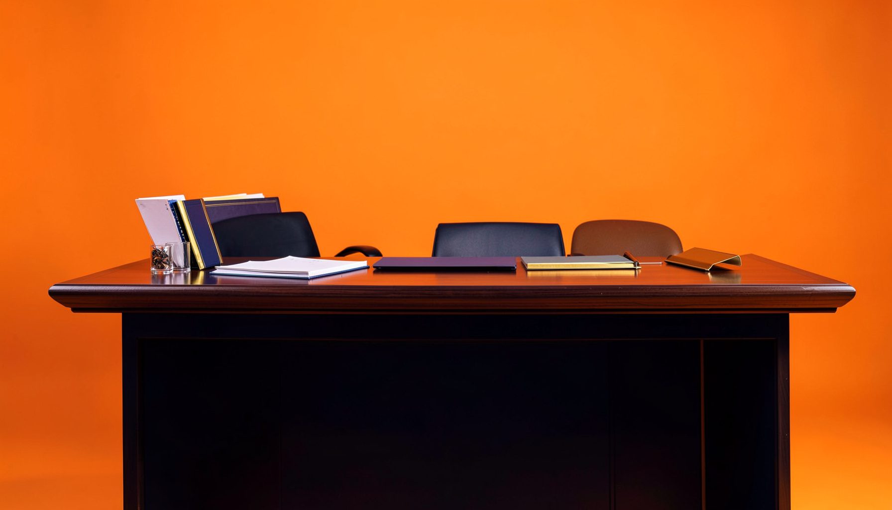 A warm conference registration desk setting with deep navy and soft gold accents, featuring neatly arranged materials on a polished wood surface
